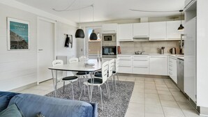 A modern kitchen with white cabinets, a dining table with chairs, and a black pendant light. - Stunning home in Otterup with WiFi (Otterup)