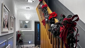Uma escadaria com corrimão de madeira, decorada com laços vermelhos e folhagem.