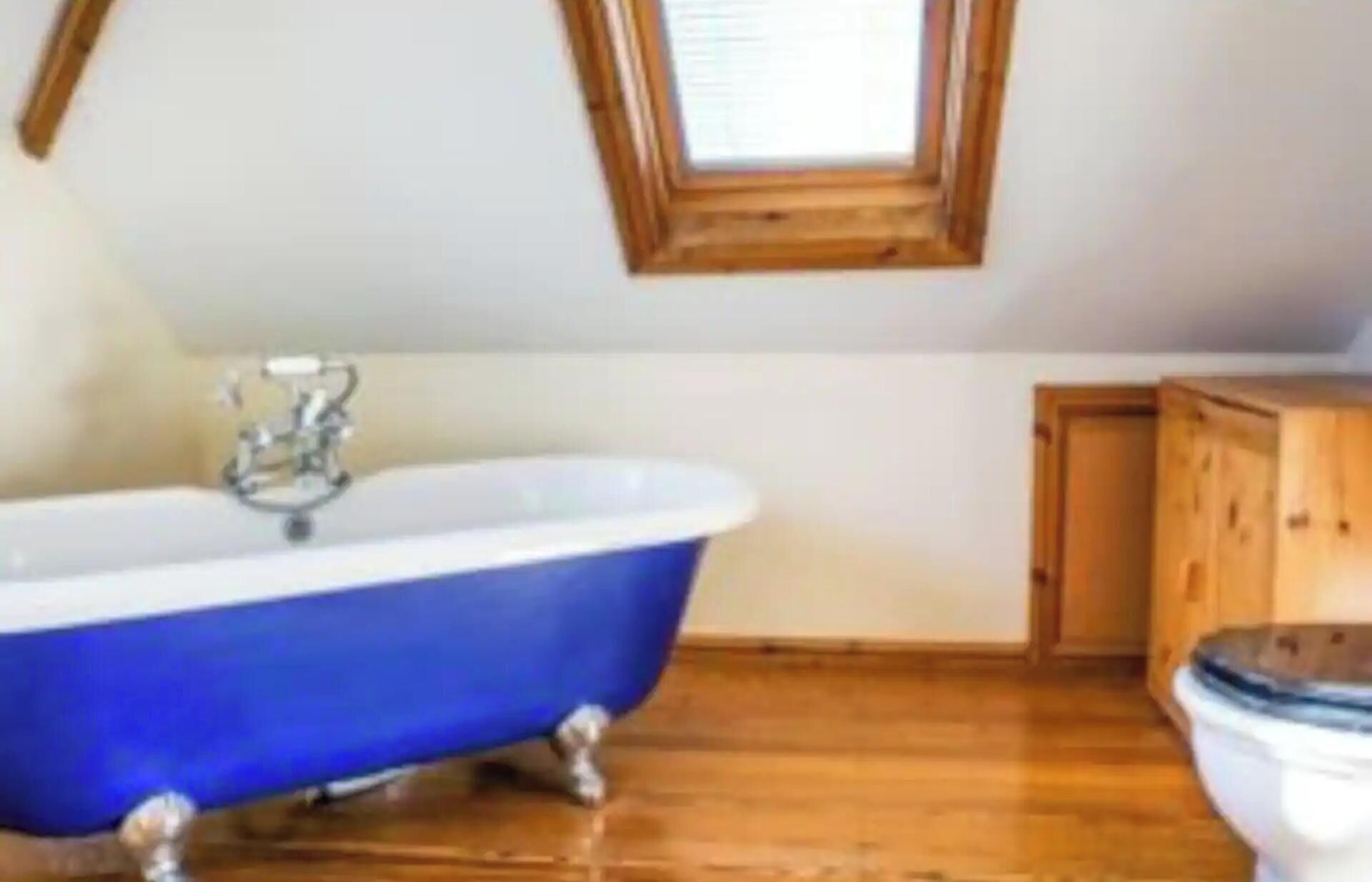 A bathroom with a freestanding bathtub, a toilet, and a wooden cabinet.