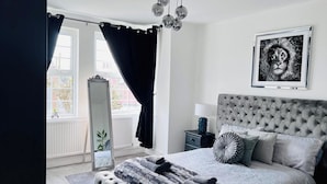 Quarto com uma cama grande, um espelho, uma mesa de cabeceira e um quadro na parede.