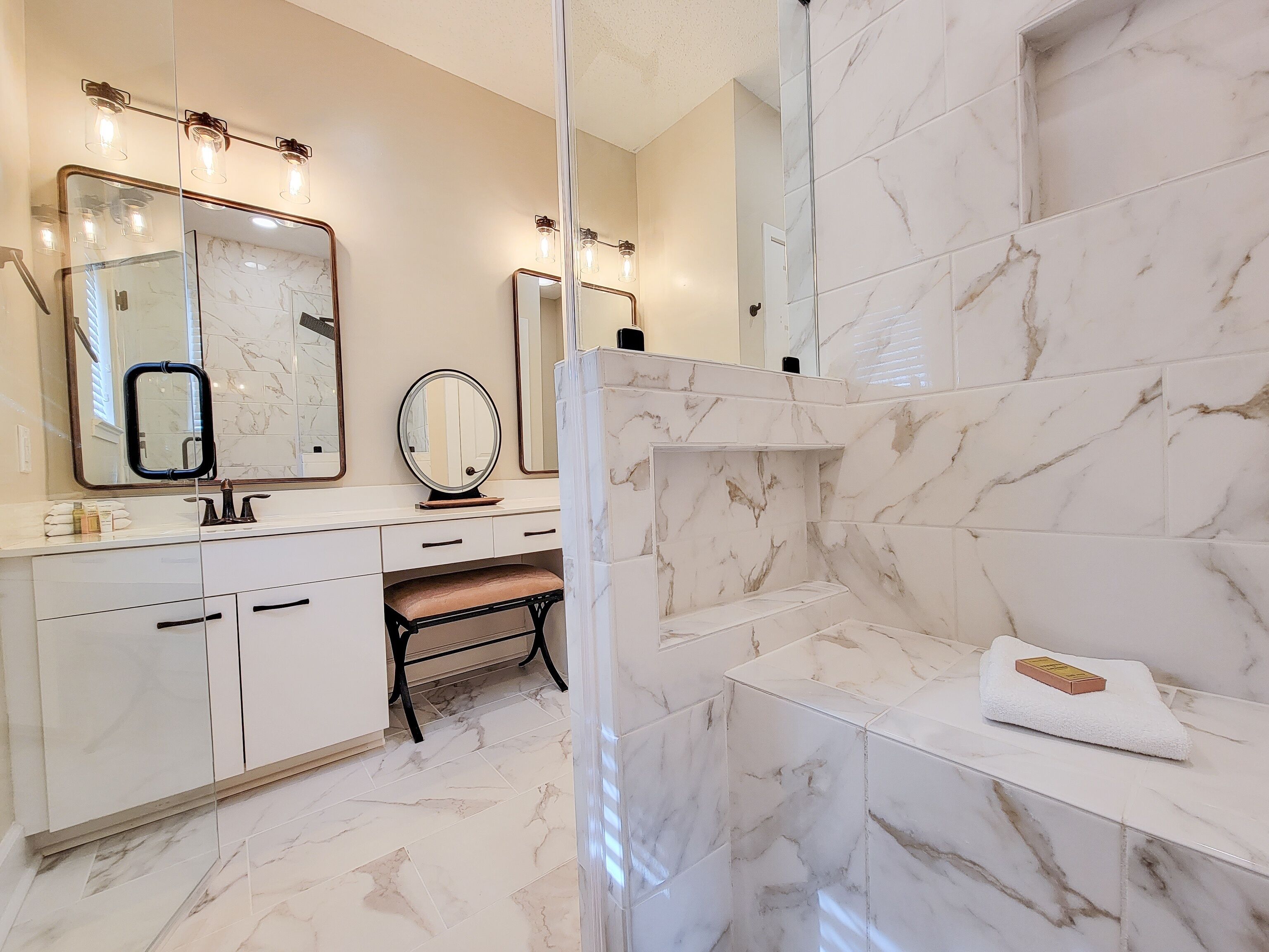 Une salle de bain moderne avec un sol en marbre, un meuble-lavabo avec un miroir et un espace douche.