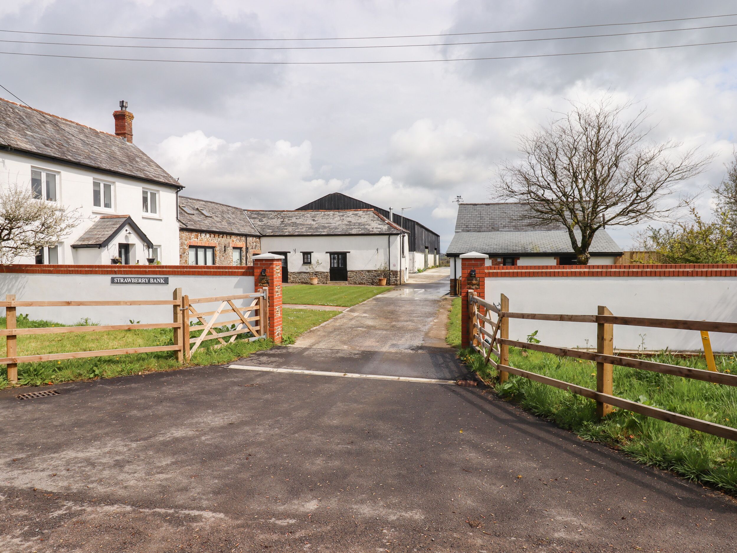 A rural road leading to a row of white buildings with a sign reading "Strawberry Bank".