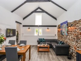 A dining area with a wooden table and chairs, a sofa, and a stone wall with a painting.