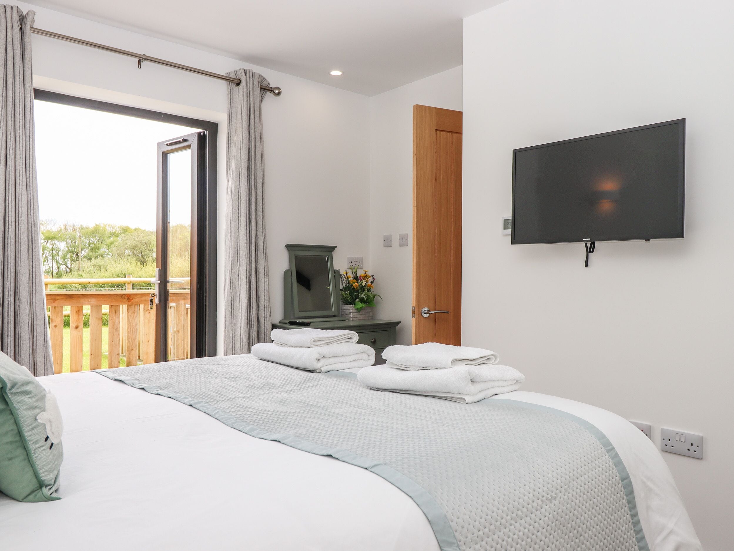 Une chambre à coucher avec un lit, une télévision, une porte en bois et une vue sur la verdure.