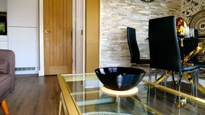 Un espace repas moderne avec une table à plateau en verre, un bol noir et une chaise noire.