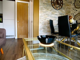 A modern dining area with a glass-top table, a black bowl, and a black chair.