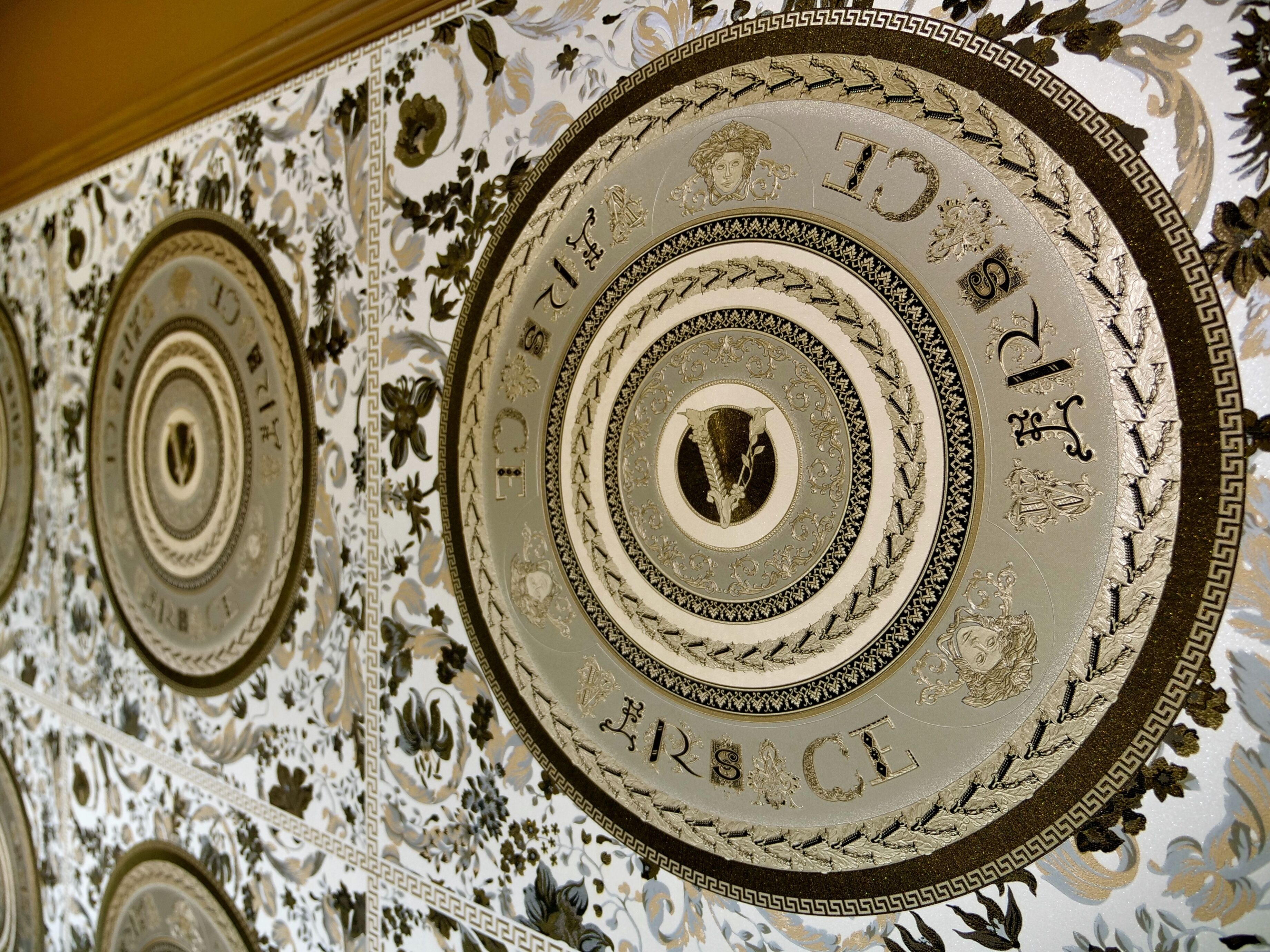 Een plafond met gedetailleerde, ronde decoraties en de tekst 'GRACE'.