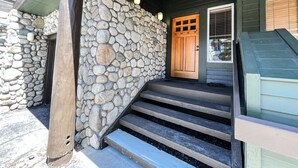 A stone-clad building with a wooden front door and steps leading to a porch.