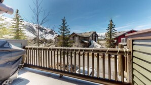 A wooden fence with a view of a mountain, a covered car, and a building with a sloped roof.