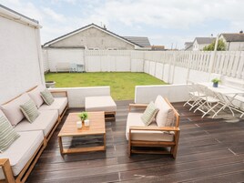 Une terrasse équipée d’un ensemble de canapés, d’une table basse et d’une table à manger avec des chaises.