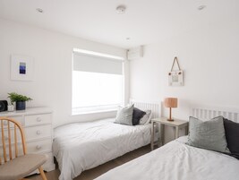 Une chambre avec deux lits, un bureau, une chaise et une fenêtre.