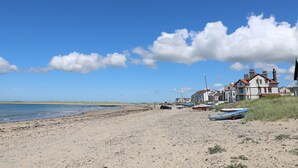 En strand med en sandstrand, några båtar och en byggnad med ett rött tak.