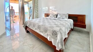 Ein geräumiges Schlafzimmer mit einem großen Bett, einem Holz-Kopfteil und einer Wand mit Steinverkleidung.