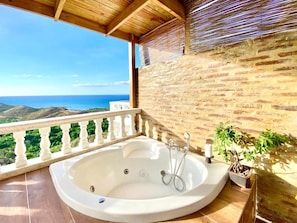 Un baño con bañera, ducha y una planta en maceta.