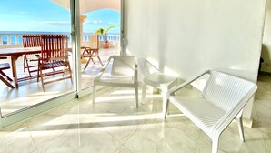 Ein Balkon mit Meerblick, ausgestattet mit Korbstühlen und einem Tisch.