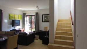 A living room with a TV, sofa, and a staircase.