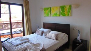 A hotel room with a bed, a nightstand, a lamp, and a window with curtains.