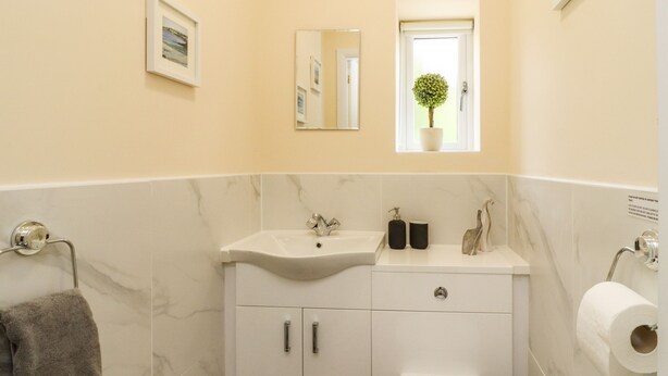 A bathroom with a white sink, mirror, toilet, and a towel rack. - Moorbottom Stables (Halifax)