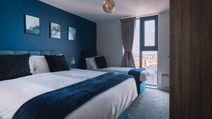 A hotel room with two beds, a large window with curtains, and artwork on the wall. - Birmingham Luxury Apartment - Free Wifi (Birmingham)