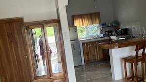 A kitchen with a wooden door, a refrigerator, a microwave, and a sink. - Seacret Studios - Cozy Jamaican Retreat Apts by RedAwning (Negril)