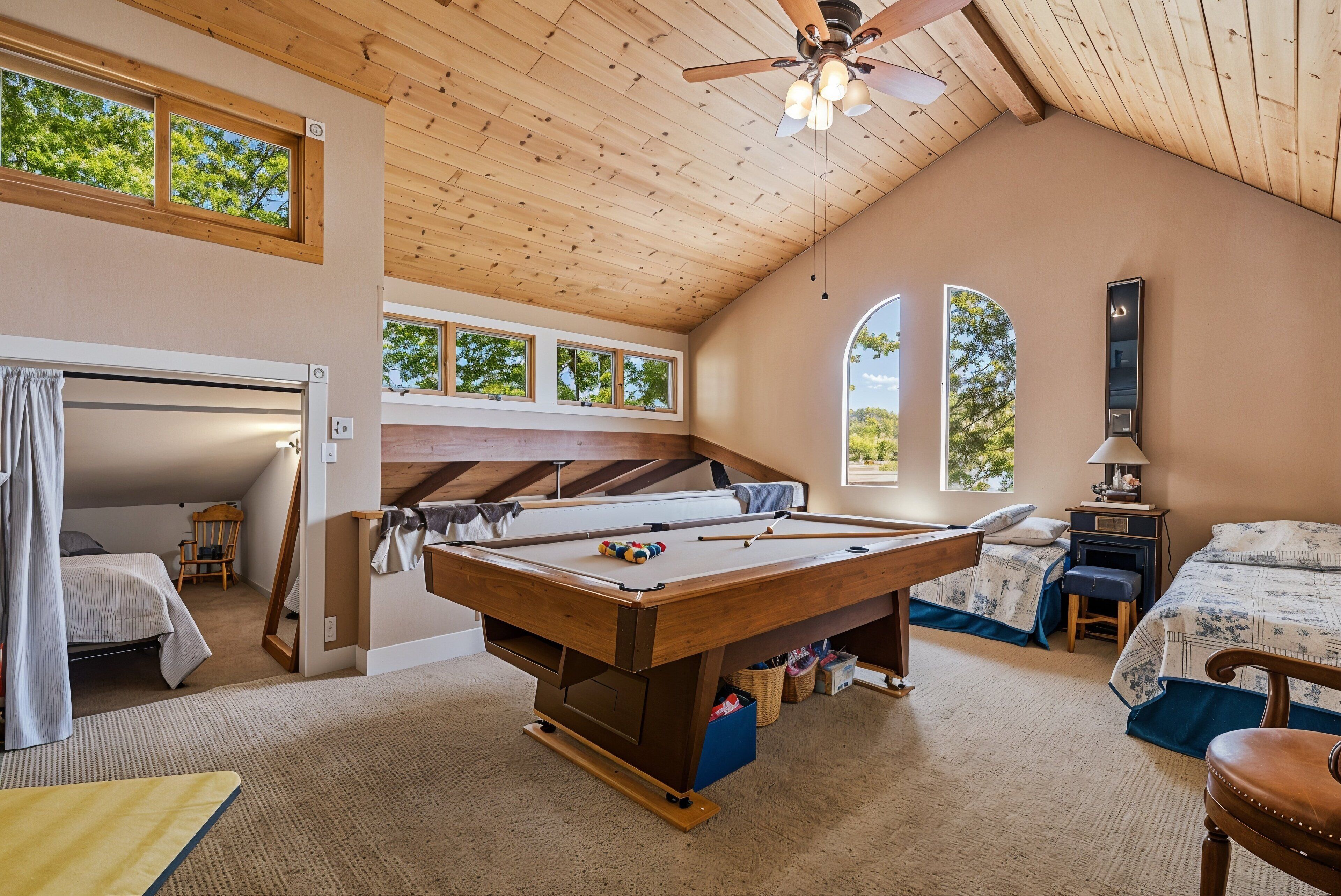 Une pièce confortable avec une table de billard, un lit et un ventilateur de plafond.