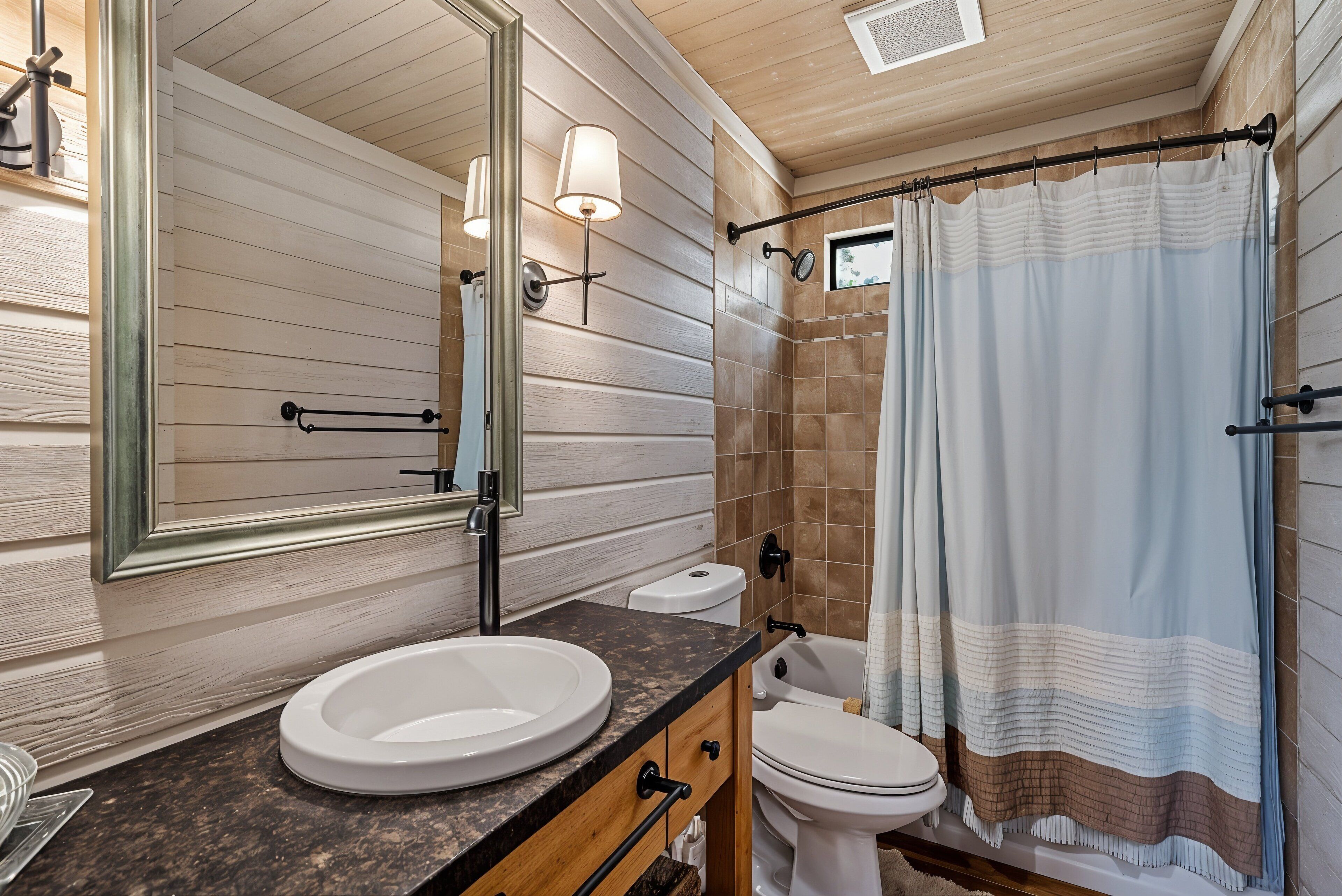 Une salle de bain avec un mur en bois, un lavabo, des toilettes, un rideau de douche et un miroir avec éclairage.