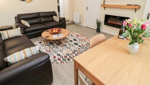 Ein Wohnzimmer mit einer Couch, einem Couchtisch und einem an der Wand montierten Fernseher.
