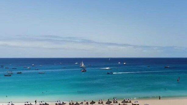 A beach with clear turquoise waters, boats, and umbrellas. - Lovely 2-bed Apartment in Santa Maria (Sal)
