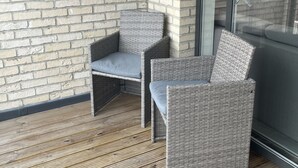 A corner of a room with a brick wall, a wicker chair, and a glass door. - Immaculate 2-bed Apartment in London (London)