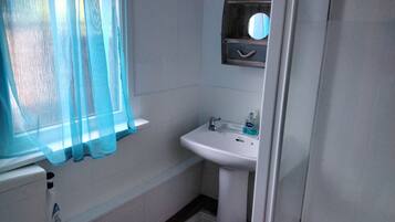 A bathroom with a white sink, a mirror above it, and a blue curtain.