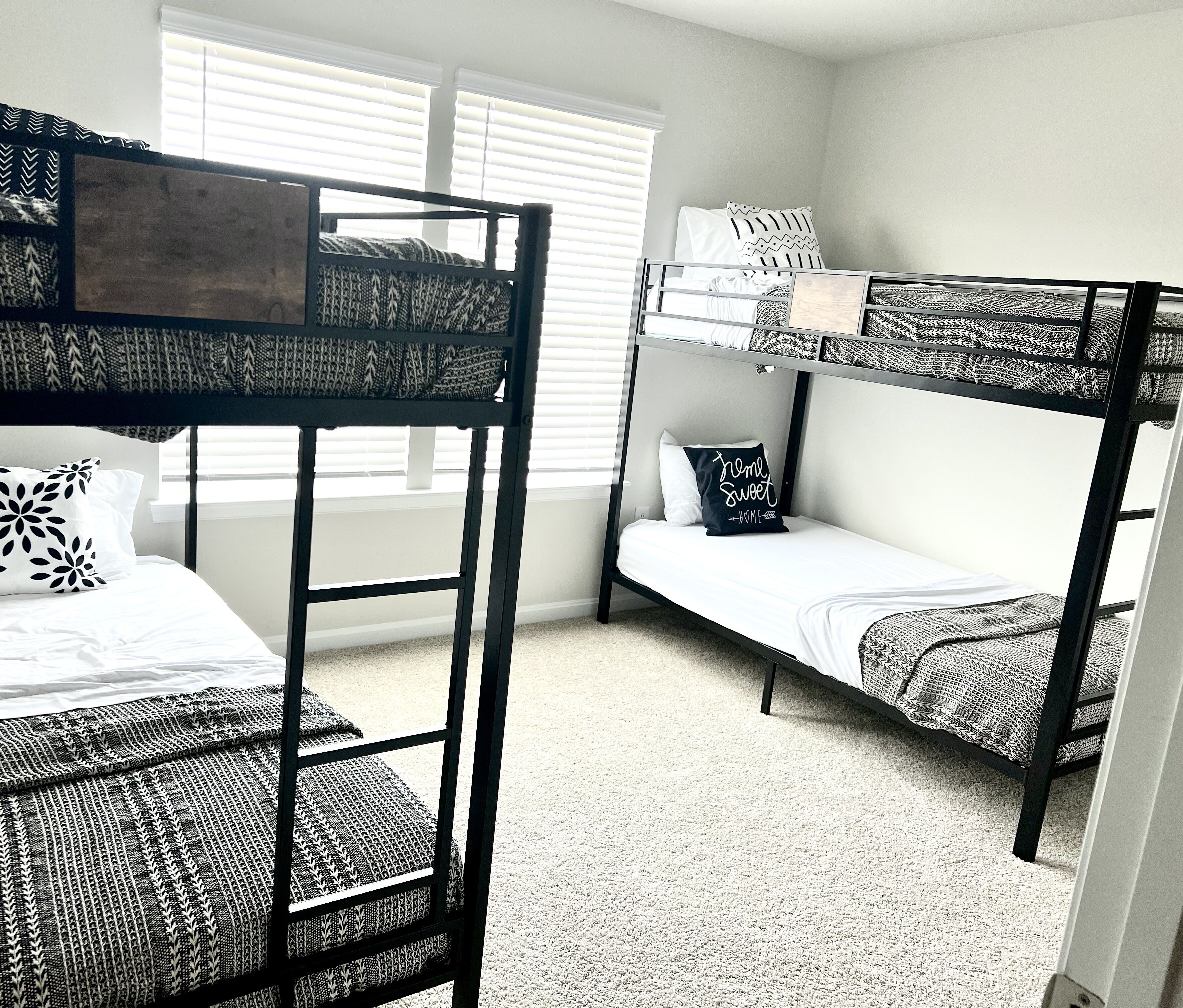 A bunk bed room with a window, a bedside table, and a pillow with text.