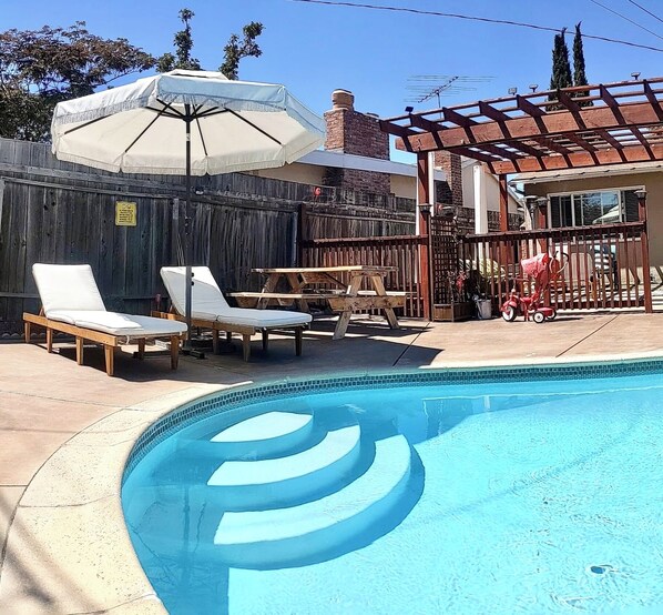 Una piscina con sillas de descanso y una sombrilla.