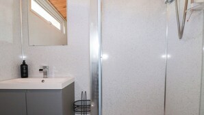 Un baño moderno con lavamanos blanco, espejo y cabina de ducha.