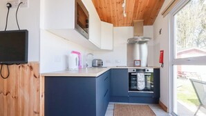 Una cocina moderna con techo de madera, horno empotrado y un amplio ventanal.