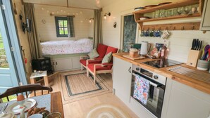 Ein gemütliches Blockhauss-Interieur mit Essbereich, einer Küche mit Holzarbeitsplatten und einem Fenster mit Blick auf einen Garten.