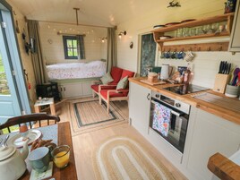 Interior acolhedor de uma cabana com área de jantar, cozinha com bancadas de madeira e janela com vista para um jardim.