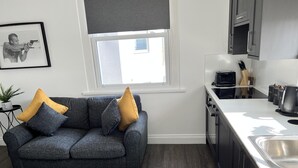 Una cucina moderna con mobili scuri, un piano di lavoro bianco e un forno integrato.