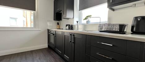 A modern kitchen with dark cabinets, a toaster, and a coffee maker on the counter.