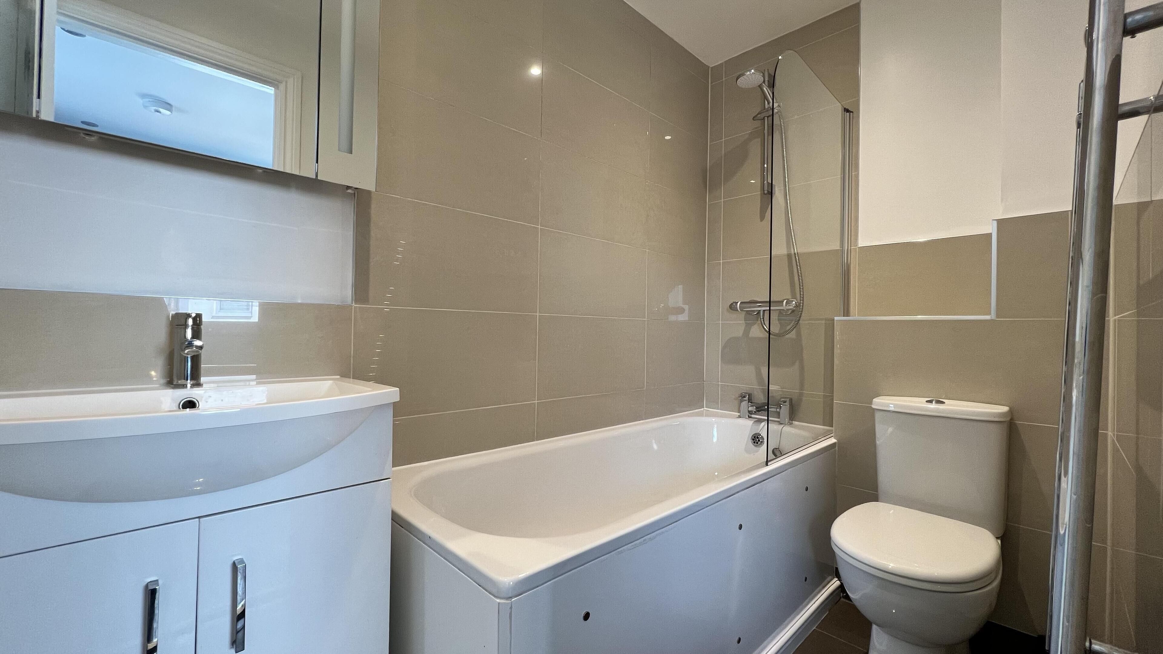 A modern bathroom with a white sink, bathtub, and toilet.