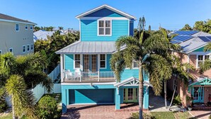 A two-story house with a blue exterior, a balcony, and a garage. - Crosswind Cottage managed by Beach Retreats (Holmes Beach)