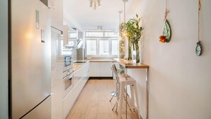 Une cuisine moderne avec des meubles blancs, un plan de travail en bois et une plante suspendue.