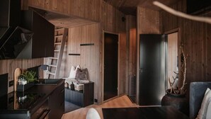 A modern interior with wooden panel walls, a black door, a staircase, and a minimalist design. - Luxurious Tree Top Cabin by the Lake (Iveland)