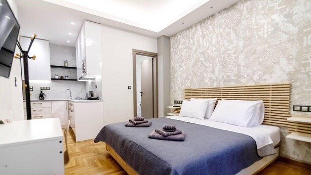 Une chambre d’hôtel moderne équipée d’un grand lit, d’un bureau et d’une kitchenette.
