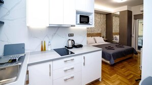 Une chambre d’hôtel compacte comprenant une kitchenette, un lit et une petite salle de bain.