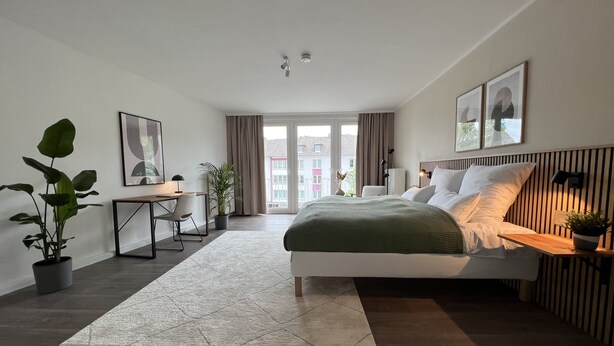 Une chambre à coucher moderne avec un lit, un bureau et des plantes en pot.