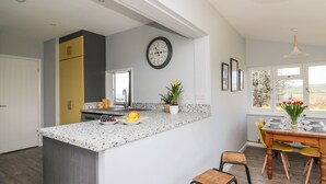 Une cuisine moderne avec un comptoir en granit, un meuble jaune et un coin repas comprenant une table et des chaises en bois.