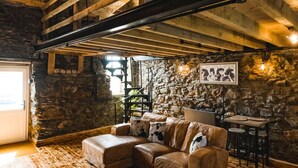 Ein rustikaler Innenraum mit freiliegenden Holzbalken, einer Steinwand und einem Ledersofa.