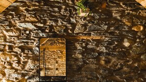 Ein rustikales Steinambiente mit einer Holztreppe, einem kleinen Holztisch und einem gerahmten Bild an der Wand.