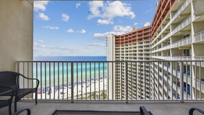 A balcony with a view of a beach and a hotel building. - Shores of Panama 1717 - 1 Bedroom + Bunk room . Gulf-Front with Oversized Balcony! 1 Condo by RedAwning (Panama City Beach)