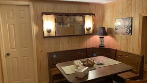 A dining area with a wooden table, chairs, a mirror, a lamp, and a framed picture on the wall. - Lake Wateree cottage (Ridgeway)